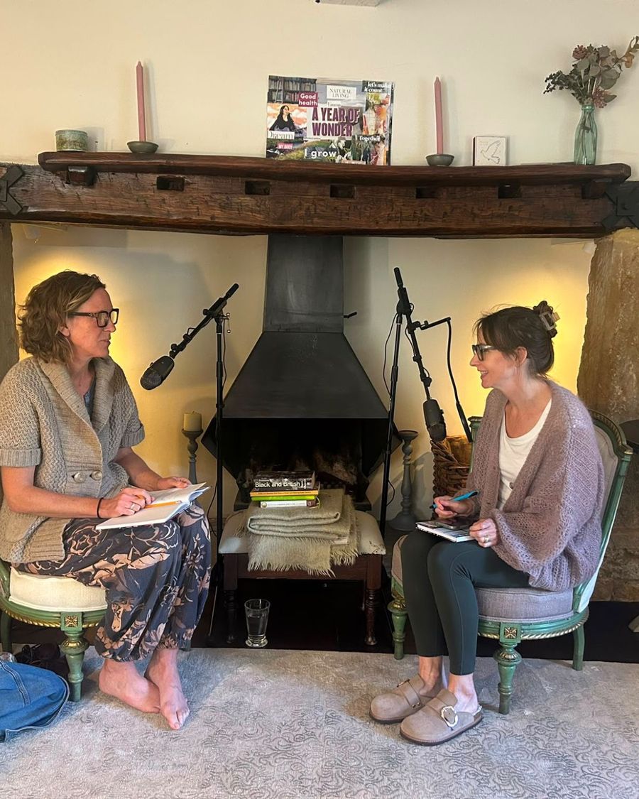 Two women chatting by a fireplace during a podcast session recorded by Snug Sessions